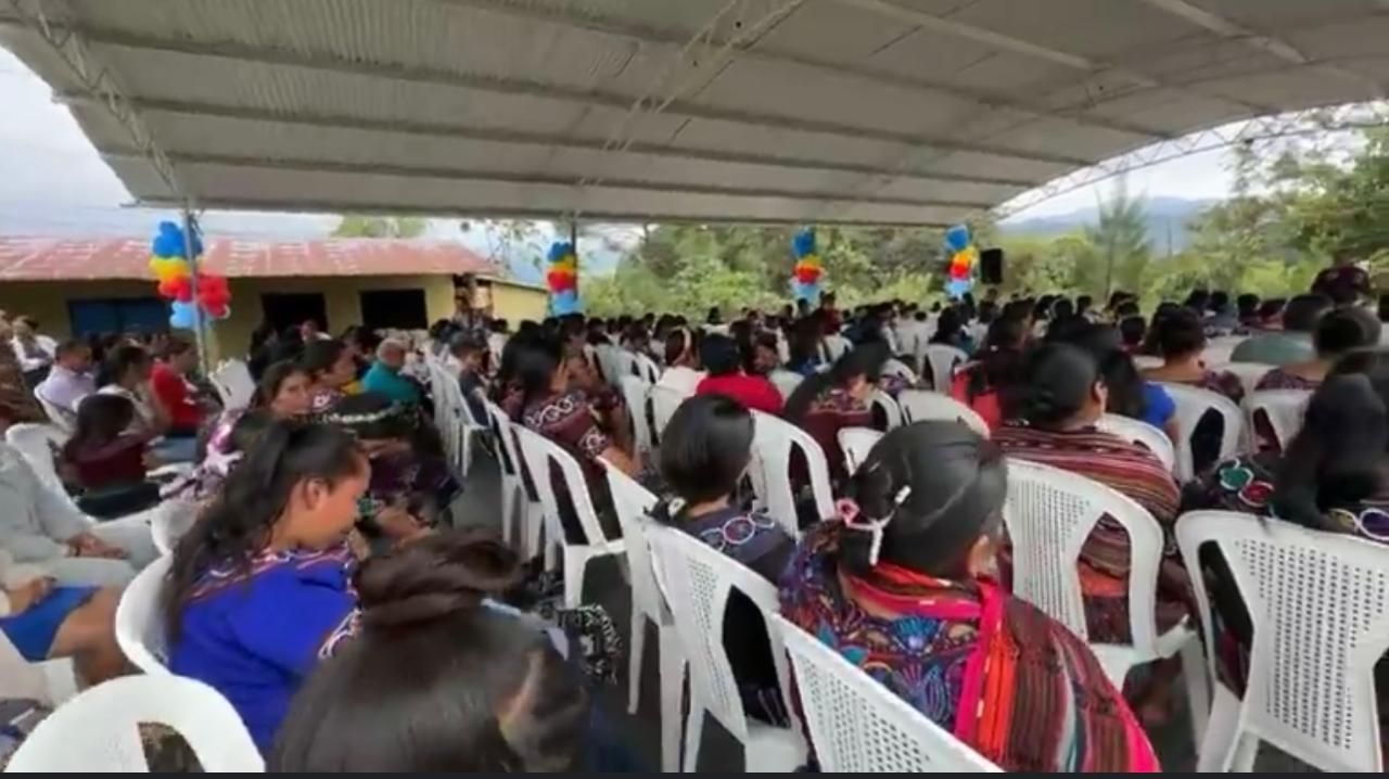 Community members seated under a canopy